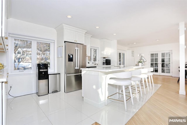 kitchen featuring a breakfast bar area, a center island, light tile patterned floors, high quality fridge, and white cabinets