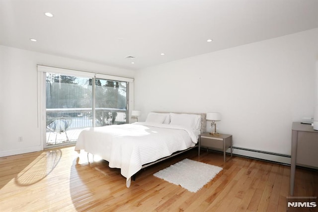 bedroom with a baseboard heating unit, light hardwood / wood-style flooring, and access to exterior