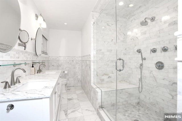 bathroom featuring tile walls, vanity, a shower with shower door, and toilet