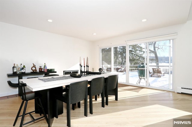 dining space with baseboard heating and light hardwood / wood-style floors