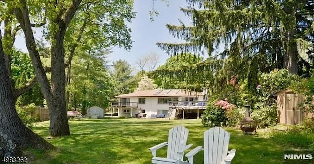 back of house with a wooden deck, a storage shed, and a yard