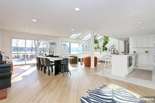 dining space featuring light wood-type flooring and a skylight