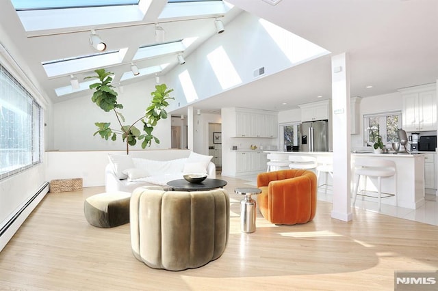 living room featuring a baseboard radiator, high vaulted ceiling, light wood-type flooring, and a skylight