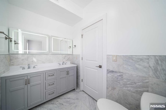 bathroom featuring vanity, tile walls, and toilet