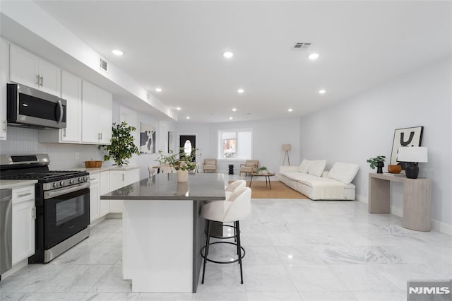 kitchen with white cabinetry, stainless steel appliances, a kitchen breakfast bar, and a kitchen island