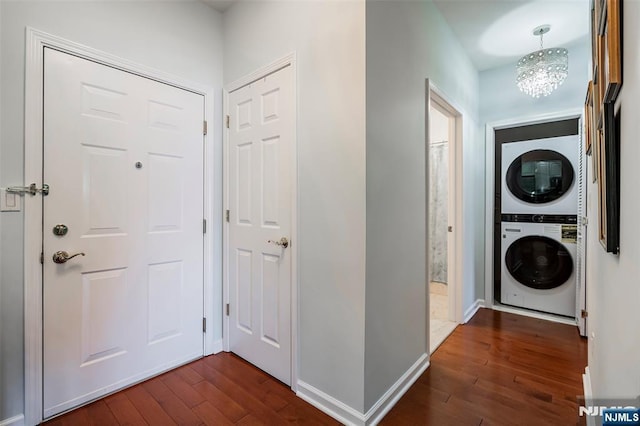 entryway with stacked washer / dryer, dark hardwood / wood-style floors, and an inviting chandelier