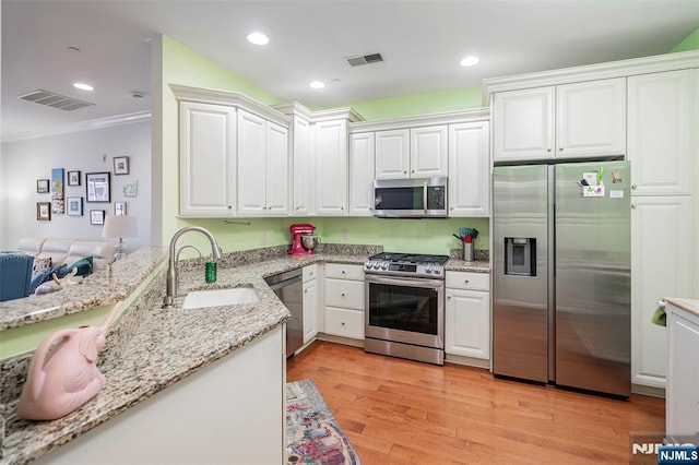 kitchen featuring white cabinetry, stainless steel appliances, sink, and light wood-type flooring