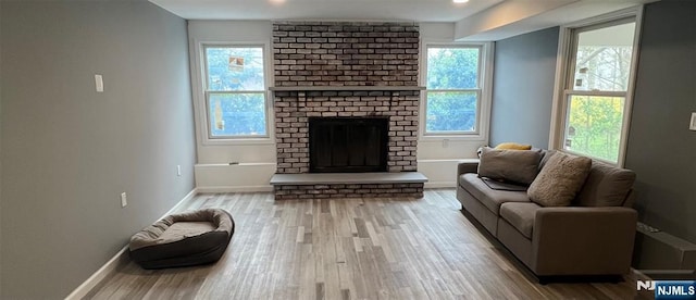 living room featuring a brick fireplace, a healthy amount of sunlight, and hardwood / wood-style floors