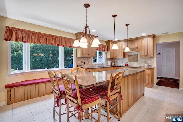 kitchen featuring light tile patterned floors, visible vents, decorative backsplash, black electric cooktop, and a center island