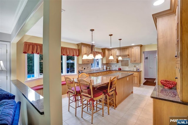 kitchen with decorative backsplash, dark stone countertops, a kitchen breakfast bar, and a kitchen island