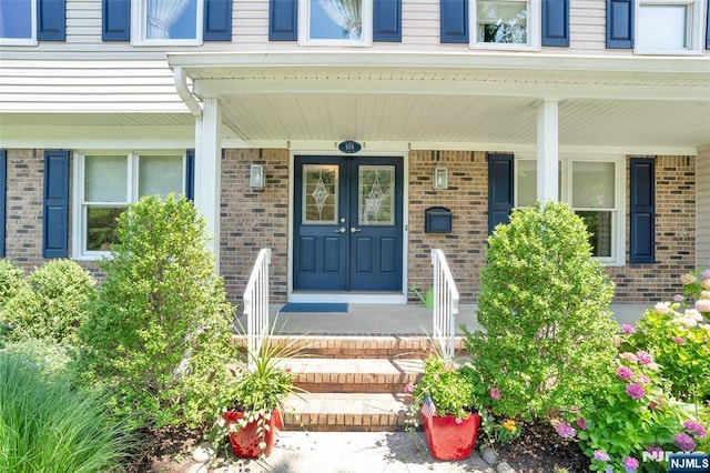 view of exterior entry featuring brick siding and a porch