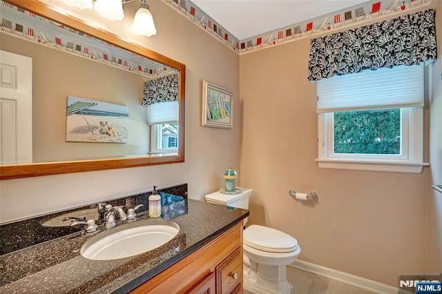 half bathroom with vanity, tile patterned floors, toilet, and baseboards