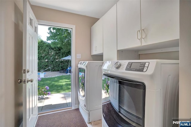 clothes washing area featuring cabinet space and washer and clothes dryer