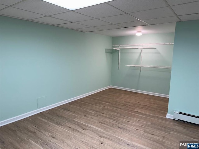 empty room featuring a baseboard radiator, baseboards, and wood finished floors