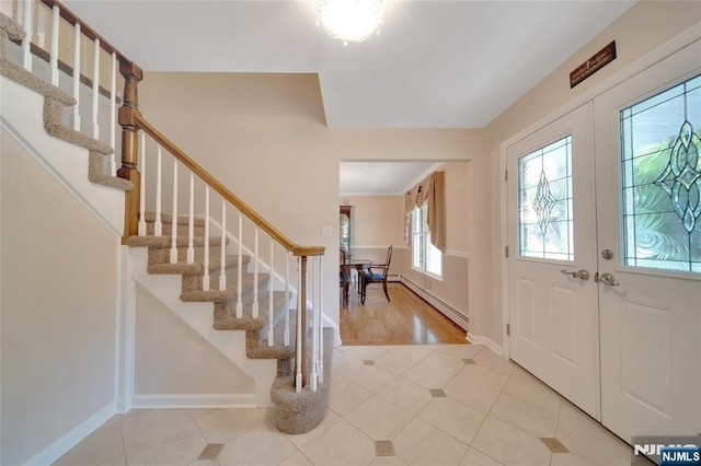 foyer featuring a baseboard heating unit, stairway, french doors, light tile patterned floors, and baseboards