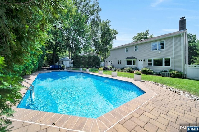 outdoor pool with a yard, a patio, an outdoor structure, and fence