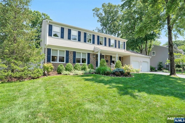 colonial-style house with brick siding, driveway, a front lawn, and a garage