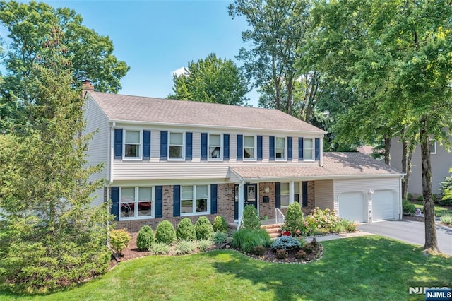 view of front facade with brick siding, a front lawn, aphalt driveway, a chimney, and a garage