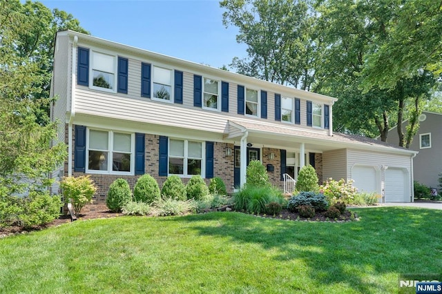 view of front of property featuring driveway, a front yard, brick siding, and an attached garage