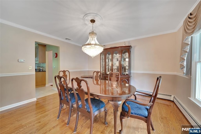 dining room featuring crown molding, a notable chandelier, light wood-style floors, and baseboards