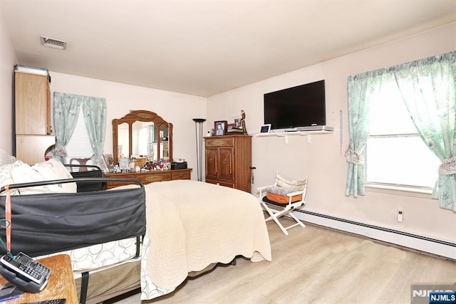 bedroom with a baseboard radiator, light hardwood / wood-style floors, and multiple windows