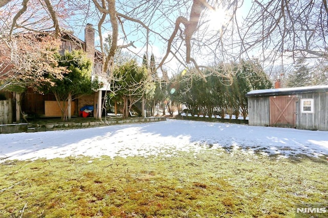 yard layered in snow featuring a storage shed