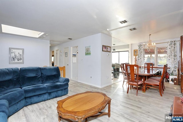 living room featuring an inviting chandelier, plenty of natural light, and light wood-type flooring