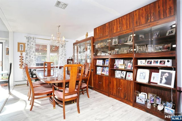 dining area featuring wood-type flooring, an inviting chandelier, and a baseboard radiator