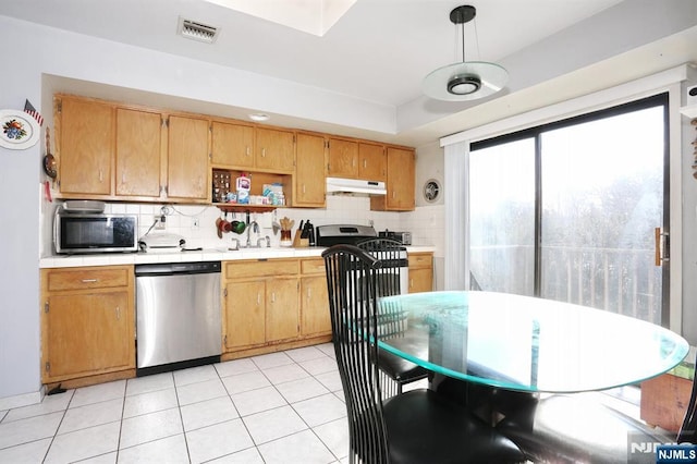 kitchen with appliances with stainless steel finishes, decorative light fixtures, light tile patterned floors, and backsplash