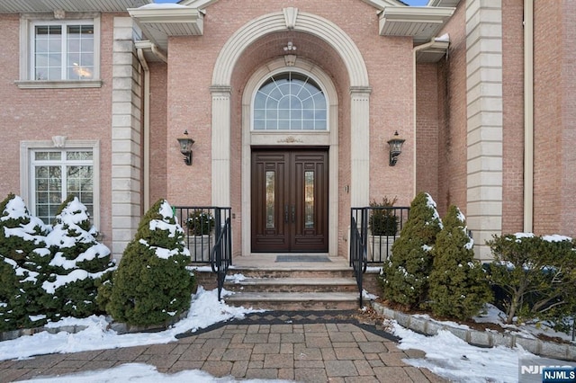 snow covered property entrance featuring french doors