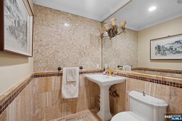 bathroom with ornamental molding, toilet, a chandelier, and tile walls