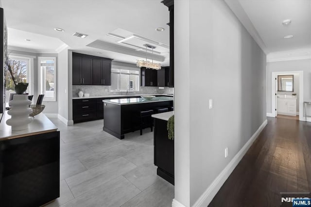 kitchen featuring pendant lighting, crown molding, a center island, and a healthy amount of sunlight