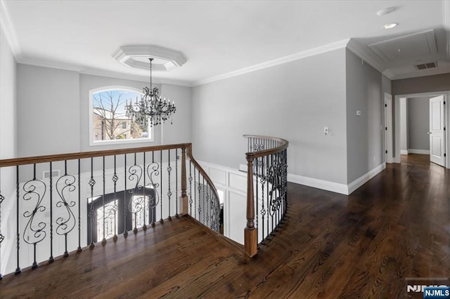 corridor with ornamental molding, dark wood-type flooring, and an inviting chandelier