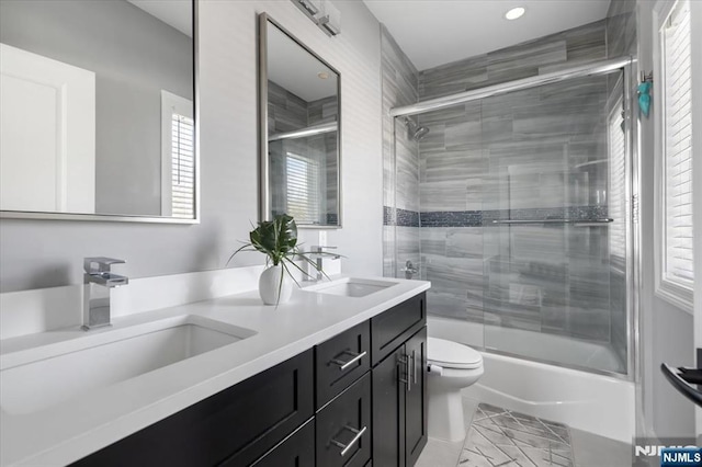 full bathroom with enclosed tub / shower combo, vanity, and toilet