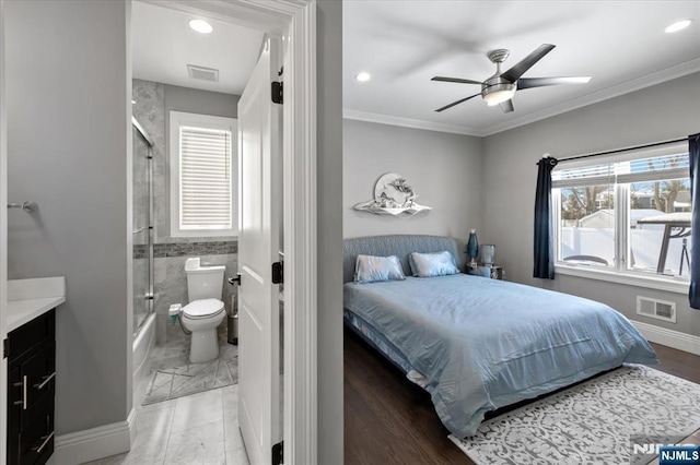 bedroom with multiple windows, ensuite bath, ornamental molding, and ceiling fan