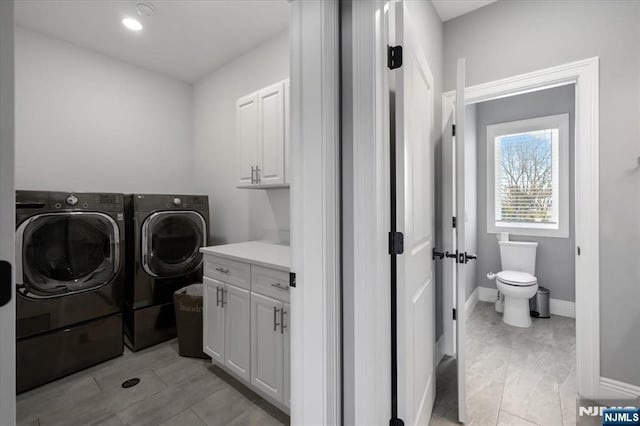 laundry area with separate washer and dryer and cabinets