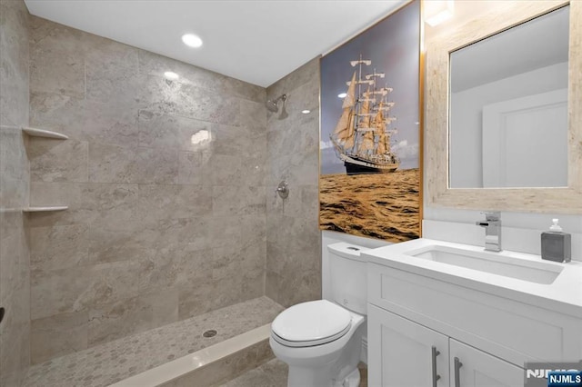 bathroom with vanity, a tile shower, and toilet