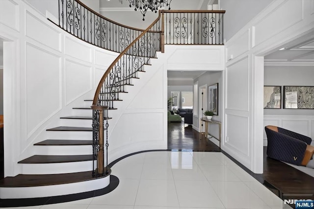 stairway featuring an inviting chandelier, ornamental molding, and tile patterned floors