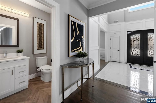 entryway featuring ornamental molding, sink, dark parquet floors, and french doors