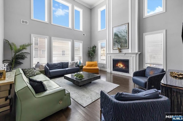 living room featuring crown molding, dark wood-type flooring, and a towering ceiling