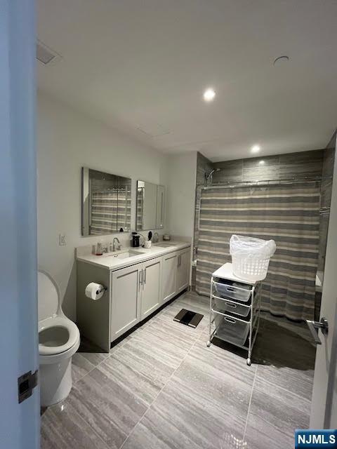 bathroom featuring vanity, tiled shower, and toilet