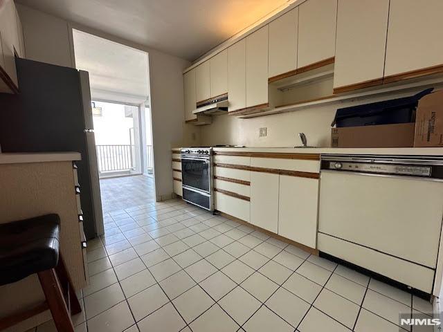 kitchen with stainless steel appliances, white cabinets, and light tile patterned flooring