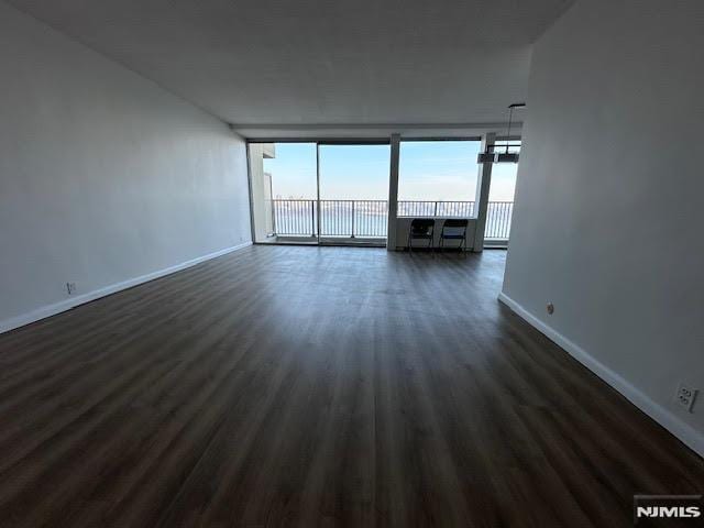 spare room featuring a wall of windows and dark hardwood / wood-style floors