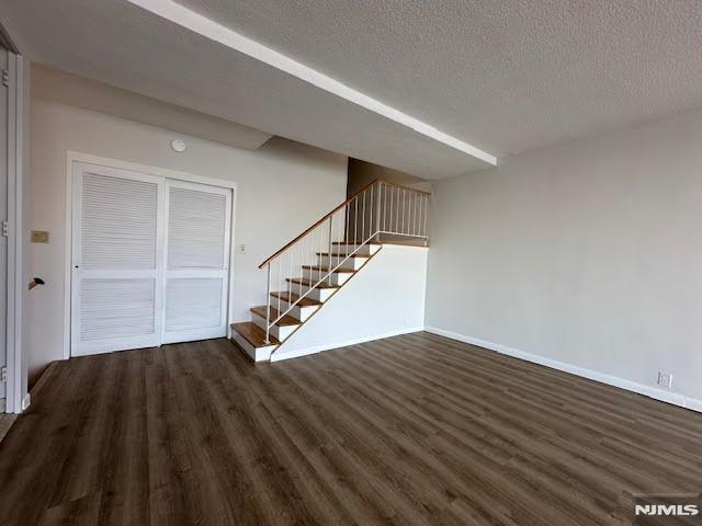 unfurnished living room featuring dark wood-type flooring and a textured ceiling