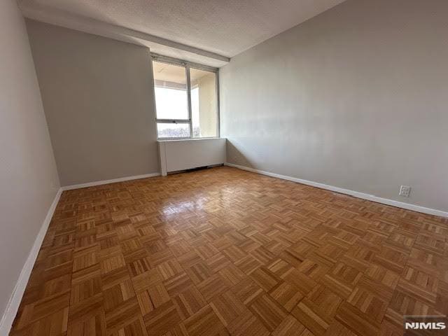 spare room with parquet flooring and a textured ceiling