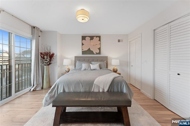 bedroom with two closets and light hardwood / wood-style floors