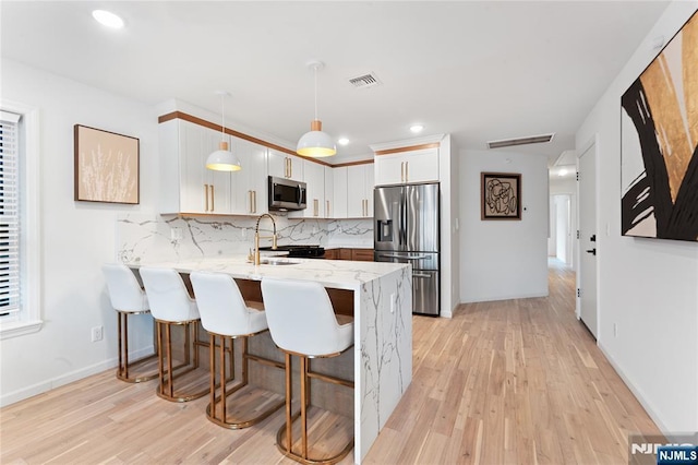 kitchen with pendant lighting, stainless steel appliances, light stone countertops, white cabinets, and kitchen peninsula