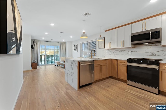 kitchen featuring sink, white cabinetry, appliances with stainless steel finishes, pendant lighting, and decorative backsplash