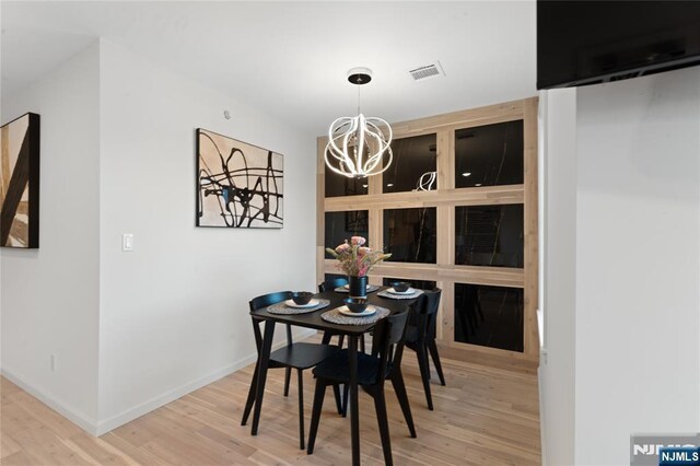 dining area with wood-type flooring and a chandelier