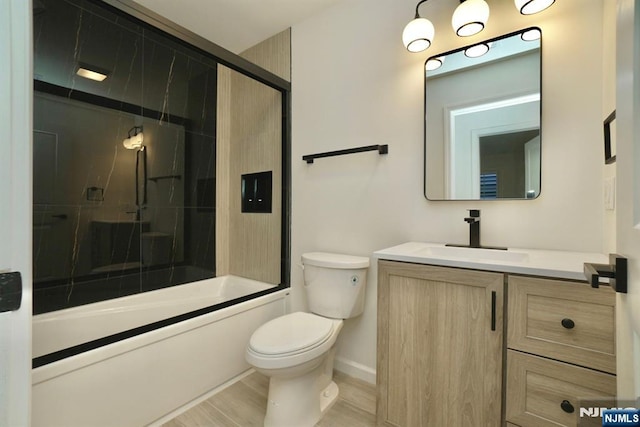 full bathroom with hardwood / wood-style flooring, bath / shower combo with glass door, vanity, and toilet